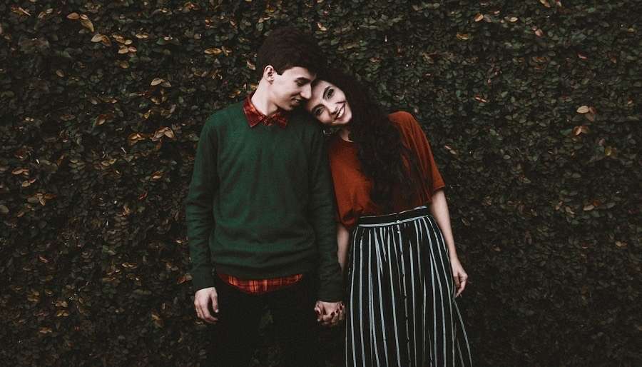 Venus in Taurus Young cute couple leaning in by hedge