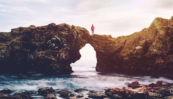 austin-neill-160132 red man standing on top of large rocks on the coast