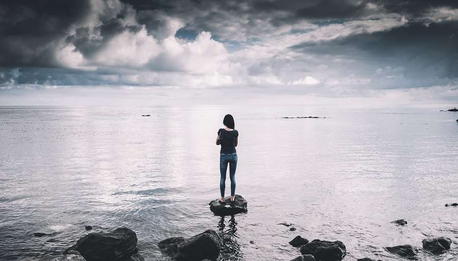 Karmic-Debt-Number Woman Standing on Empty Beach looking at Horizon