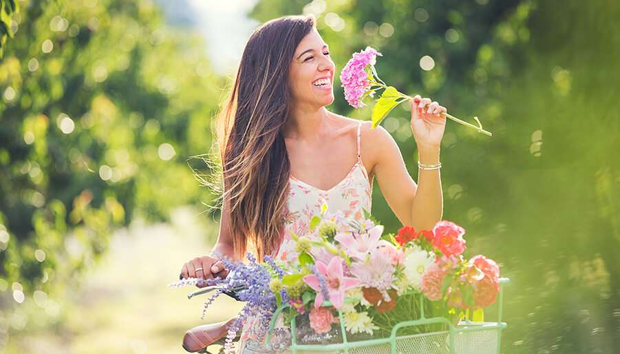 flower-essences woman on bike smelling flowers