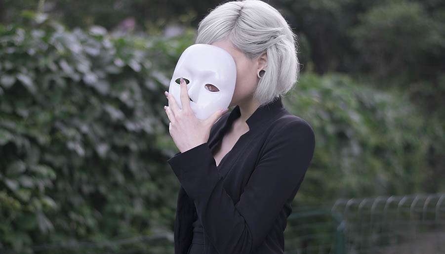 imposter women holding white mask to her face